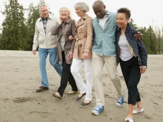 mature friends walking along the beach